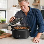 Man tilt het glazen deksel van de slowcooker op in de keuken, stoofpot met wortel