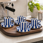 Vier blauwe kopjes met schotels op een dienblad naast de espressomachine