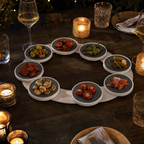 Serveerbaan met tapas op een donkere eettafel bij kaarslicht