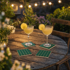 Cocktailglazen op groene mozaïek onderzetters op een tuintafel in de avond